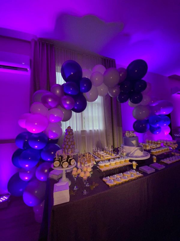 Purple and white balloon garland over a dessert table