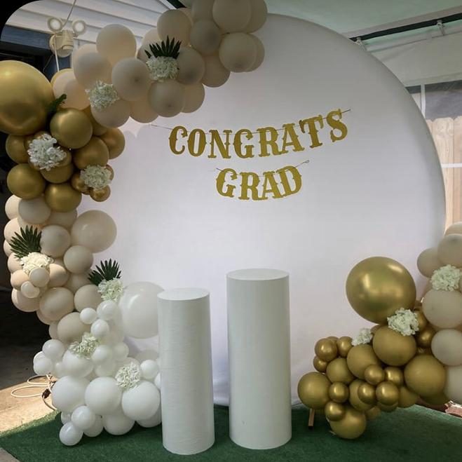 Balloon garland with white flowers around a Congrats Grad backdrop